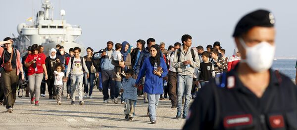 Refugiados sirios acompañados por carabineros italianos después de desembarcar en Augusta, Italia - Sputnik Mundo