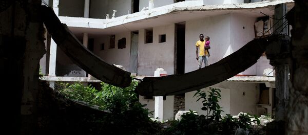 Un padre sostiene a su hija fuera de su habitación en Puerto Príncipe - Sputnik Mundo