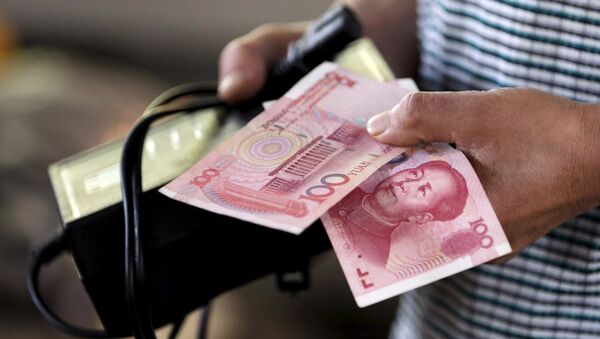 A customer holds a 100 Yuan note at a market in Beijing, August 12, 2015 - Sputnik Mundo