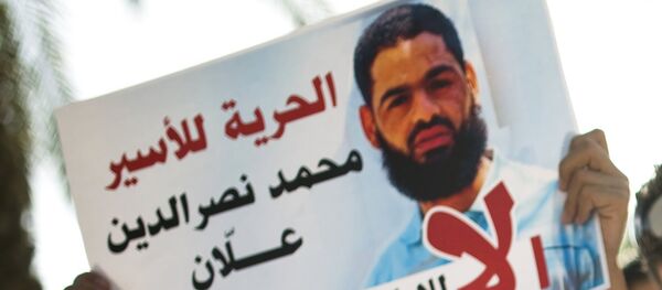 Familiares protestan contra alimentación a la fuerza de prisionero palestino Mohammed Allan, visto en el póster - Sputnik Mundo