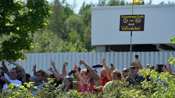 Manifestantes durante la visita de Algela Merkel al albergue para refugiados en Heidenau - Sputnik Mundo