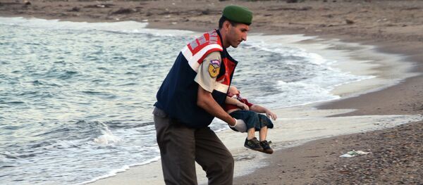 Un oficial de la policía paramilitar lleva el cuerpo sin vida de Aylan Kurdi - Sputnik Mundo