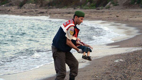 Un oficial de la policía paramilitar lleva el cuerpo sin vida de Aylan Kurdi - Sputnik Mundo