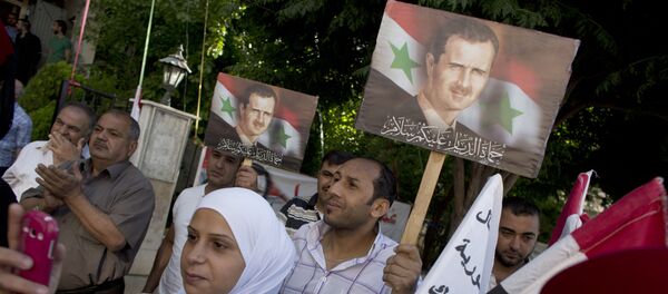La gente tiene retratos del presidente sirio Bashar Assad fuera de un centro de votación en Damasco La gente tiene retratos del presidente sirio Bashar Assad fuera de un centro de votación en Damasco - Sputnik Mundo