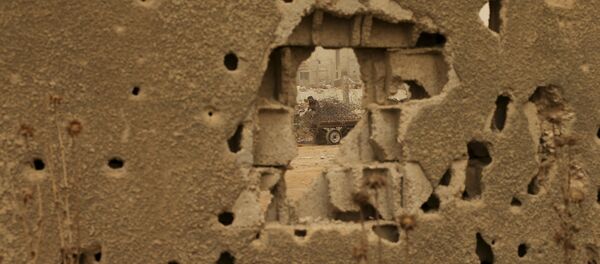 A Palestinian man, pictured through a damaged wall, collects steel during a sandstorm in Gaza September 9, 2015 - Sputnik Mundo