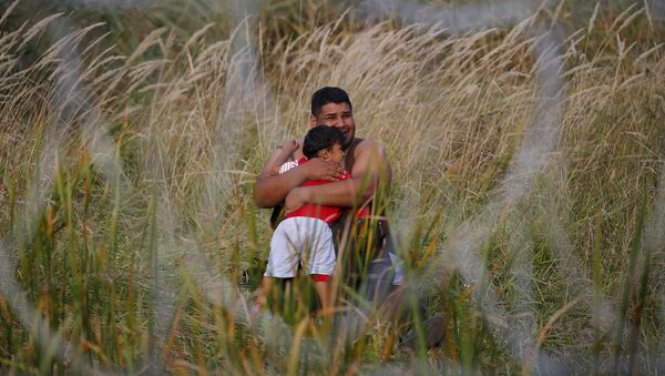Migrante con su niño en Asotthalom, Hungría - Sputnik Mundo