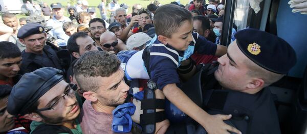Policía croata ayuda a un niño de refugiado a subirse al autobús en Tovarnik, Croacia - Sputnik Mundo