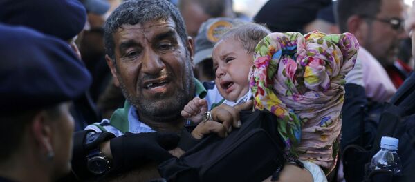 Refugiado abraza a una niña esperan en cola para subirse al autobús en Tovarnik, Croacia - Sputnik Mundo