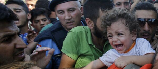 Refugiado abraza a una niña al esperar en la cola para subirse al autobús en Tovarnik, Croacia - Sputnik Mundo