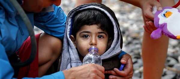 Voluntarios ayudan a un niño de refugiado Voluntarios ayudan a un niño de refugiado - Sputnik Mundo