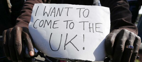 Migrante con un póster que dice Quiero llegar al Reino Unido! - Sputnik Mundo