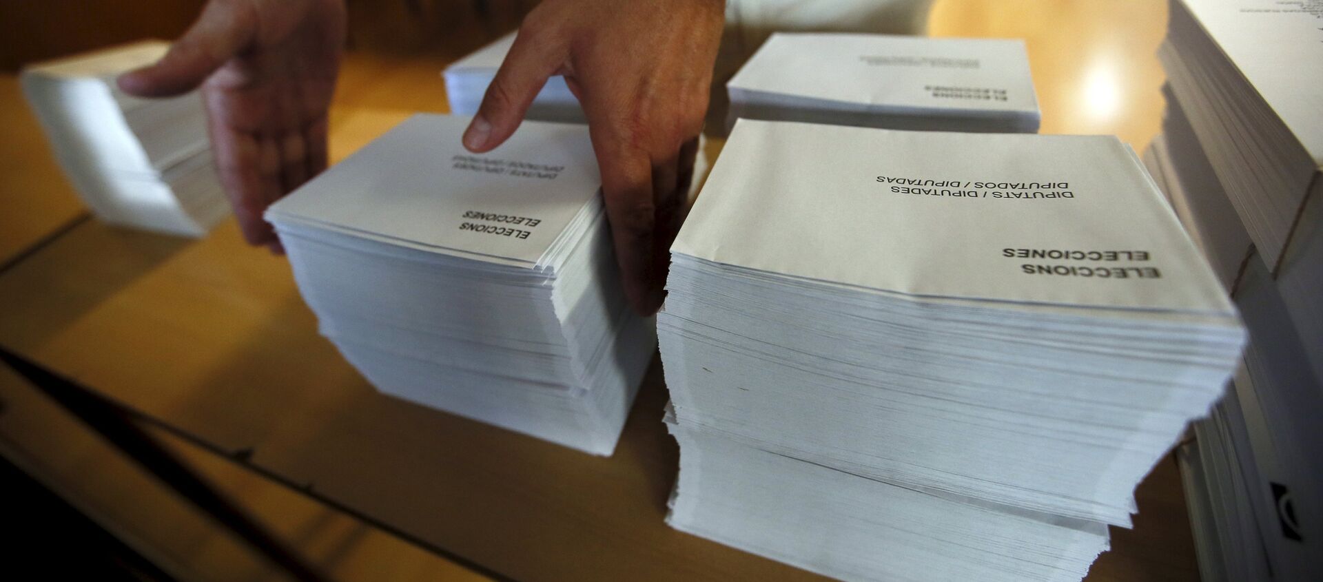 A man places ballots and envelopes on a table as the polling station is prepared inside a school in Barcelona, Spain, September 25, 2015.  - Sputnik Mundo, 1920, 03.02.2021