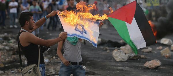 A Palestinian protester burns a replica Israeli flag - Sputnik Mundo