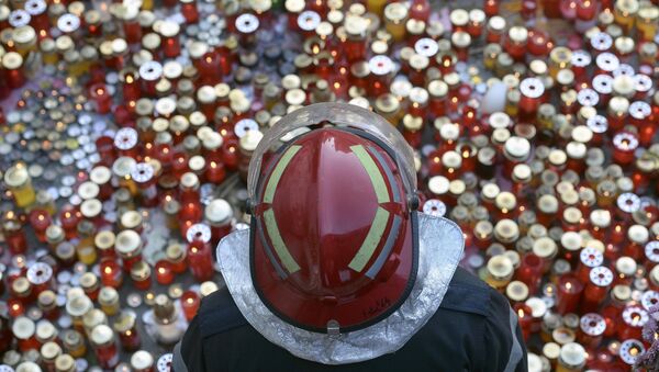 Bombero se encuentra junto a un monumento que conmemora a las víctimas de un incendio en Bucarest - Sputnik Mundo