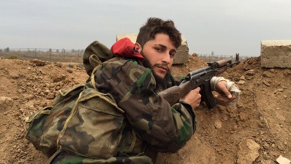 A pro-regime gunman holds a position at a military airport held by Syrian troops and pro-regime militias in the northeastern Syrian city of Deir Ezzor on December 12, 2014, five days after they repelled an attack by jihadists from the Islamic State (IS) group on the airport. - Sputnik Mundo