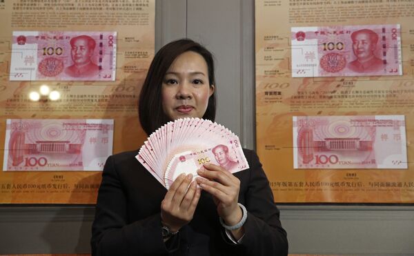 A staff member displays the new version of the 100-yuan RMB (US 15.7 dollars) banknotes for photographers at the Bank of China Tower in Hong Kong - Sputnik Mundo