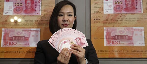 A staff member displays the new version of the 100-yuan RMB (US 15.7 dollars) banknotes for photographers at the Bank of China Tower in Hong Kong - Sputnik Mundo