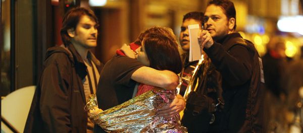 Hombre abraza a una mujer cerca de la sala de Bataclan antes de ser evacuados por autobús - Sputnik Mundo