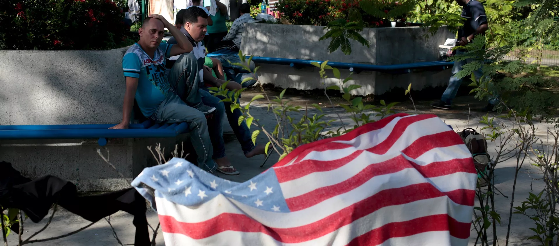 Cuban migrants sit near a beach towel with the U.S. flag Cuban migrants sit near a beach towel with the U.S. flag - Sputnik Mundo, 1920, 04.02.2021