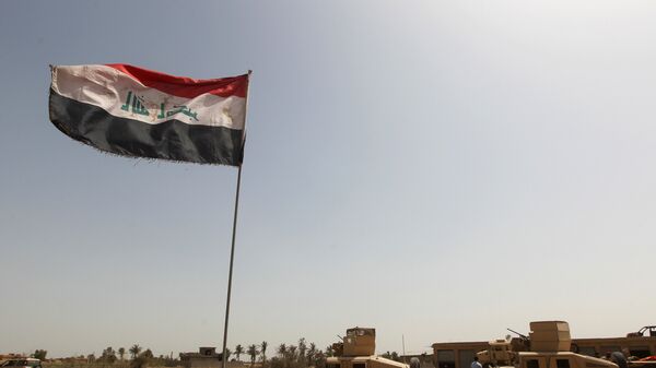 Iraqi forces stand by armed vehicles parked near an Iraqi flag as they patrol an area in the Garma district, west of the Iraqi capital Baghdad - Sputnik Mundo