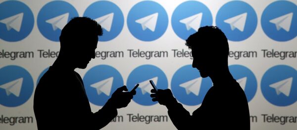 Two men pose with smartphones in front of a screen showing the Telegram logos in this picture illustration taken in Zenica, Bosnia and Herzegovina November 18, 2015. - Sputnik Mundo