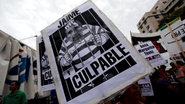 A relative of victims of a 2012 train crash holds up a sign with a picture depicting former Secretary of Transport Ricardo Jaime outside a courtroom in Buenos Aires, Argentina, December 29, 2015 - Sputnik Mundo