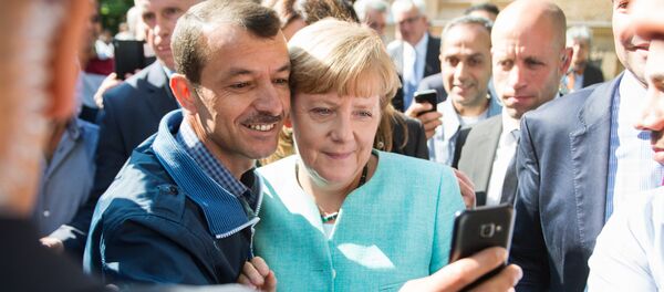 Un refugiado se hace un selfie con Angela Merkel (archivo) - Sputnik Mundo