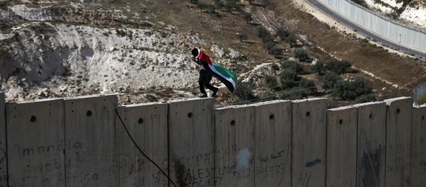 Un palestino camina sobre el muro de Cisjordania, construido por Israel - Sputnik Mundo