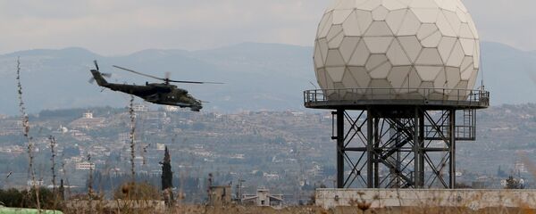 Un helicóptero vuela cerca de un radar en la base militar rusa Hmeymim en Siria - Sputnik Mundo