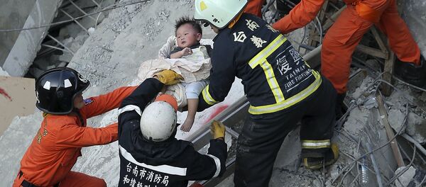 Equipo de rescate ayuda a un niño tras el sismo en Taiwán - Sputnik Mundo