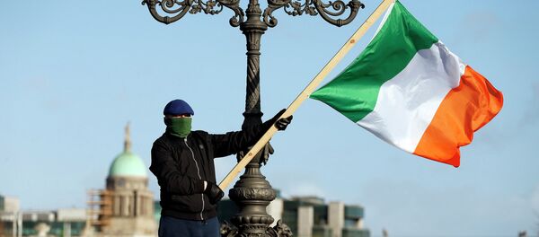 Un manifestante con la bandera de Irlanda - Sputnik Mundo
