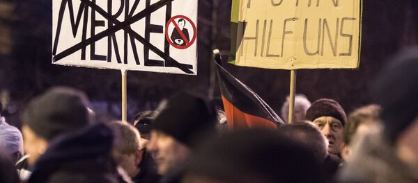 Protestas en Erfurt, Alemania. El cartel de la izquierda pone el nombre tachado de la canciller alemana Ángela Merkel: Merkel. El cartel de la derecha dice: Putin,  ayúdanos - Sputnik Mundo