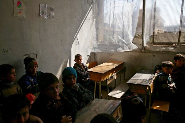 Niños sirios en una escuela destruida por bombardeos en Damasco - Sputnik Mundo