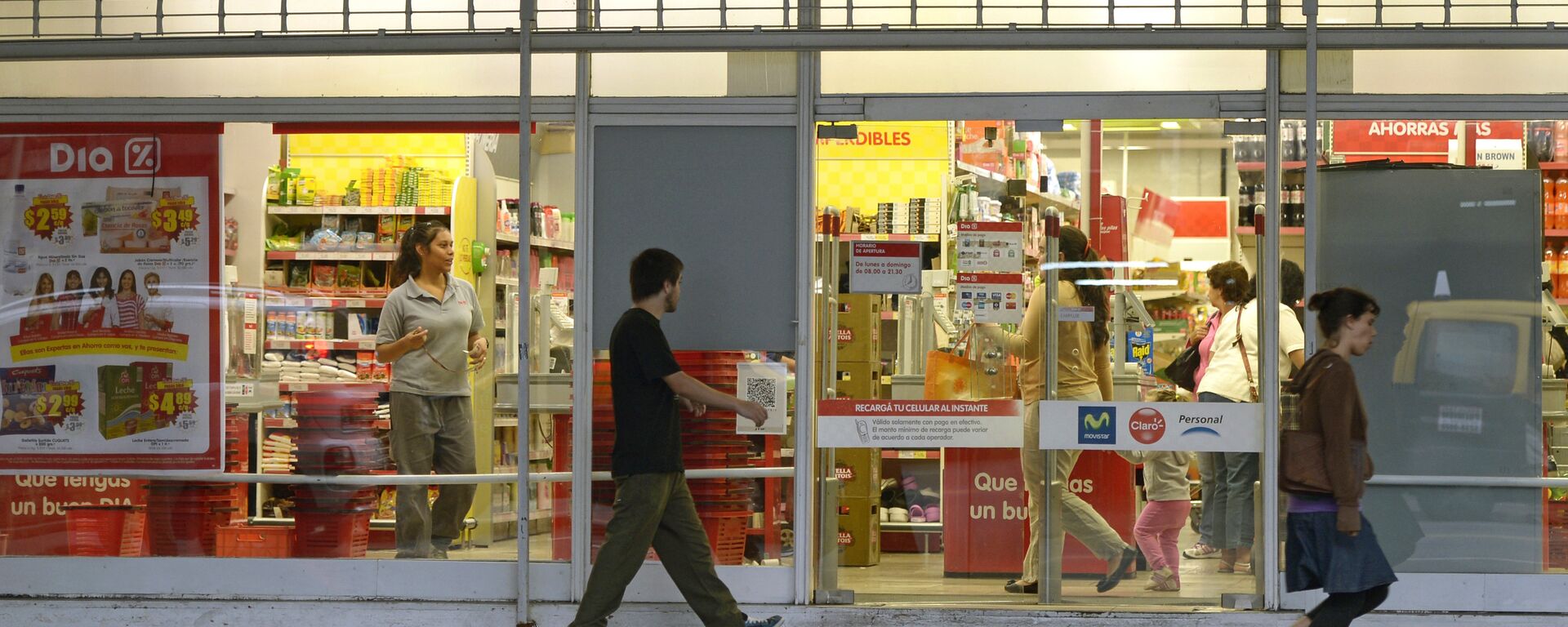 People walk past a supermarket with a promotional poster on its window in Buenos Aires on February 19, 2013. Argentines fear inflation may reach a rate of 30% this year, after a new price freeze has gone into effect until April 1. - Sputnik Mundo, 1920, 03.05.2022