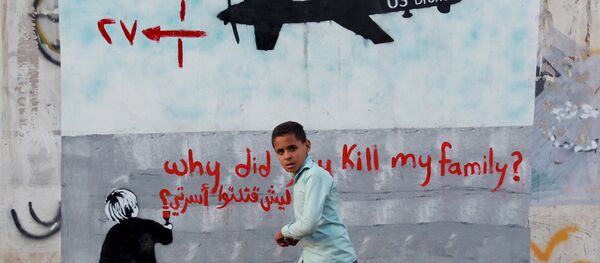 A Yemeni boy (C) walks past a mural depicting a US drone and reading  Why did you kill my family on December 13, 2013 in the capital Sanaa. - Sputnik Mundo