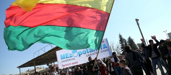 A Kurdish man waves a large flag of the Kurdish People's Protection Units (YPG) political wing, the Democratic Union Party (PYD), during a demonstration against the exclusion of Syrian-Kurds from the Geneva talks in the northeastern Syrian city of Qamishli on February 4, 2016 - Sputnik Mundo