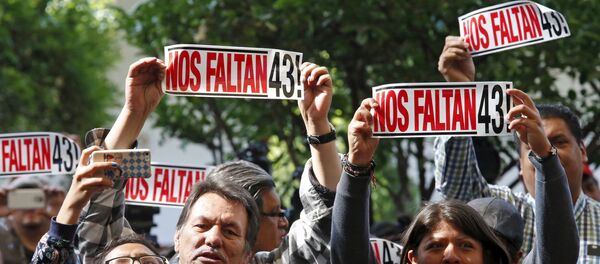 Activists hold a sign during the delivery of the final report of the 43 missing students from the Ayotzinapa teacher's training college by IACHR members, in Mexico City Activists hold a sign during the delivery of the final report of the 43 missing students from the Ayotzinapa teacher's training college by IACHR members, in Mexico City - Sputnik Mundo