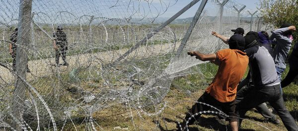 Migrantes intentan derrumbar una parte de la valla fronteriza entre Grecia y Macedonia - Sputnik Mundo
