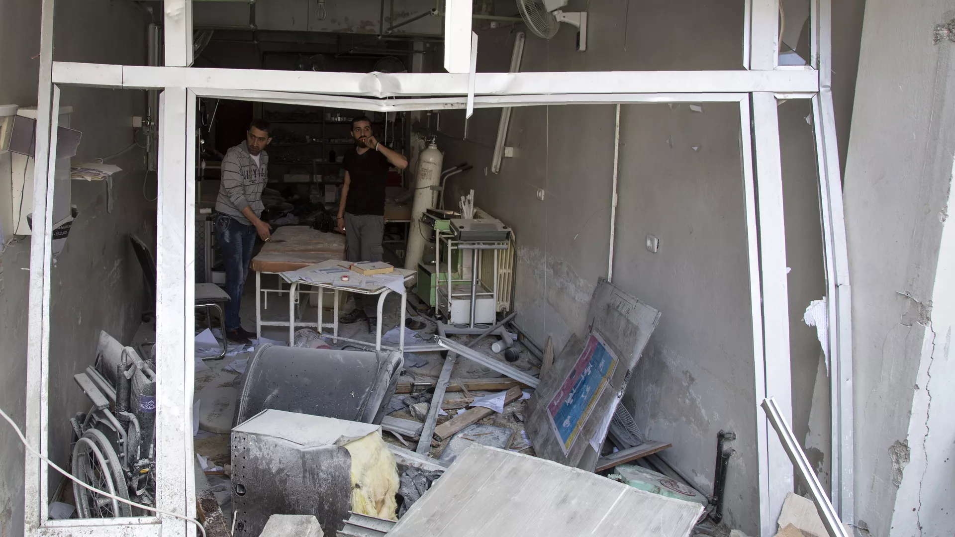 A picture taken on April 28, 2016 shows Syrian men inspecting the damage at the Al-Quds hospital building following reported airstrikes on the rebel-held neighbourhood of Sukkari in the northern city of Aleppo. 