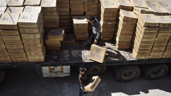 Syrian men unload aid parcels provided by the UN World Food Programm (WFP) and the Syrian Arab Red Crescent in the rebel-held town of Al-Houla, on the northern outskirts of Homs in central Syria - Sputnik Mundo