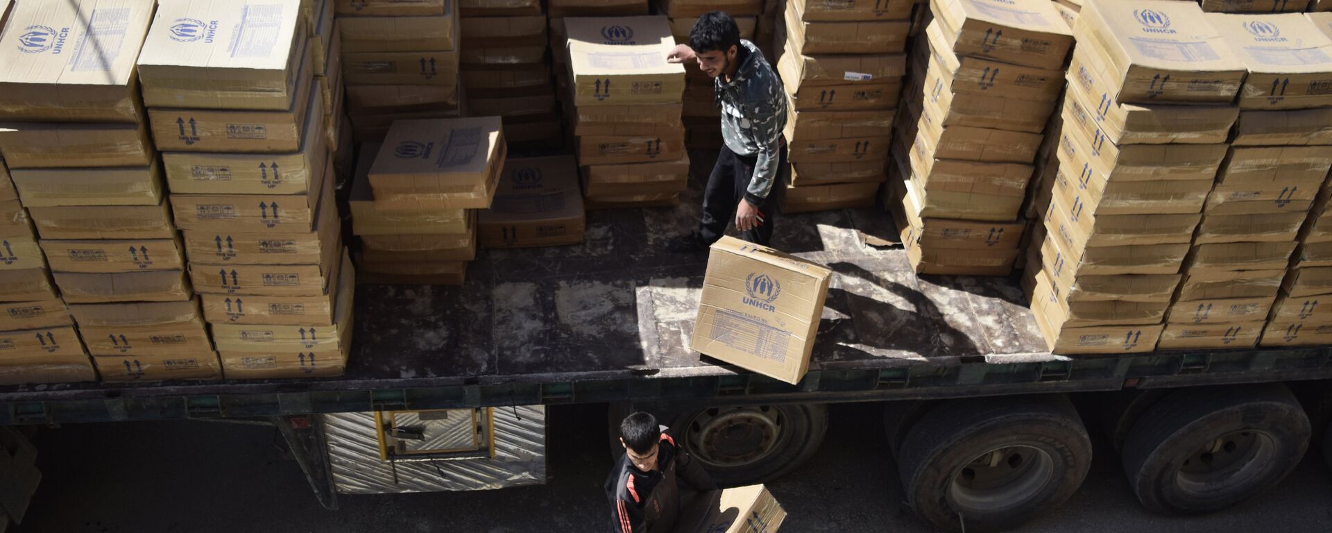 Hombres sirios descargan paquetes de ayuda proporcionados por el Programa Mundial de Alimentos (PMA) de la ONU y la Media Luna Roja Árabe Siria Hombres sirios descargan paquetes de ayuda proporcionados por el Programa Mundial de Alimentos (PMA) de la ONU y la Media Luna Roja Árabe Siria - Sputnik Mundo, 1920, 09.01.2023