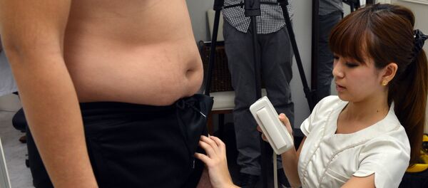 Una médica japonesa pesa a un hombre (archivo) - Sputnik Mundo