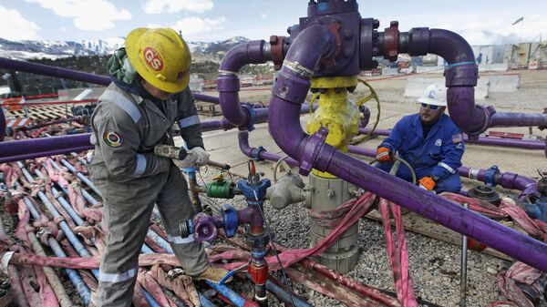 Workers tend to a well head during a hydraulic fracturing operation outside Rifle, in western Colorado - Sputnik Mundo