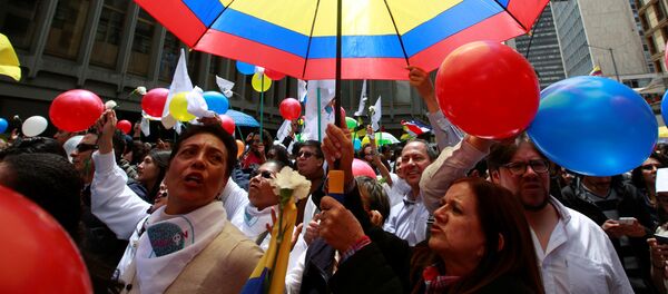 Colombianos celebrando con un paraguas con los colores de su bandera - Sputnik Mundo