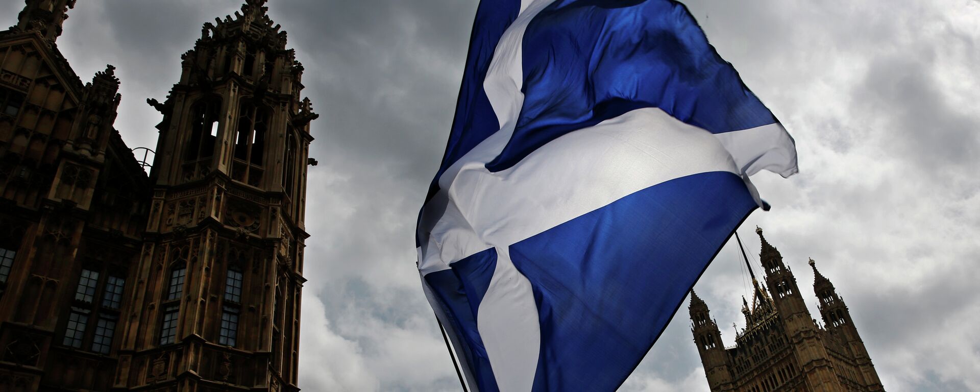 A member of public flies a giant Scottish Saltire flag outside the Houses of Parliament shortly before Scotland First Minister Nicola Sturgeon posed with newly-elected Scottish National Party (SNP) MPs during a photocall in London on May 11, 2015 A member of public flies a giant Scottish Saltire flag outside the Houses of Parliament shortly before Scotland First Minister Nicola Sturgeon posed with newly-elected Scottish National Party (SNP) MPs during a photocall in London on May 11, 2015 - Sputnik Mundo, 1920, 30.03.2021