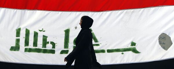 An Iraqi woman walks her national flag during a celebration marking the the departure of US troops from Iraq in Baghdad's Adhamiyah neighbourhood. File photo - Sputnik Mundo