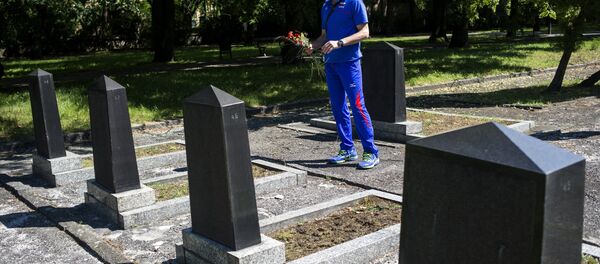 Un hombre deposita flores en una tumba - Sputnik Mundo