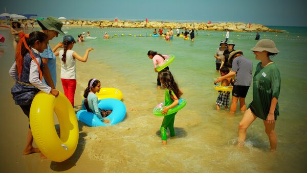 Voluntarios de la ONG Min el Bahar ayudan a niños palestinos a meterse en el agua, en la playa de Tel Baruch, en Tel Aviv Voluntarios de la ONG Min el Bahar ayudan a niños palestinos a meterse en el agua, en la playa de Tel Baruch, en Tel Aviv - Sputnik Mundo