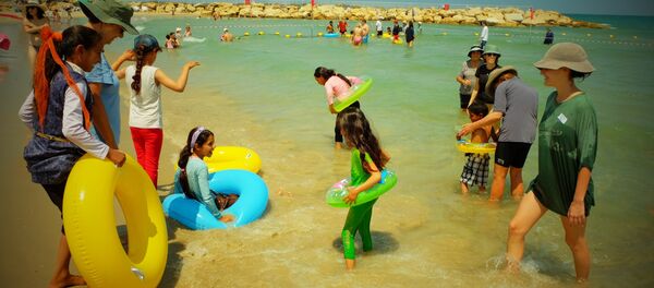 Voluntarios de la ONG Min el Bahar ayudan a niños palestinos a meterse en el agua, en la playa de Tel Baruch, en Tel Aviv - Sputnik Mundo