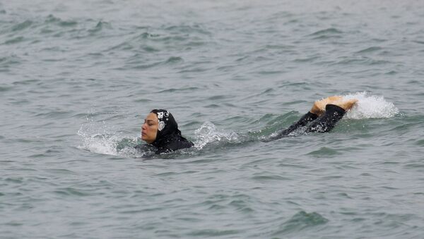 A Muslim woman wears a burkini, a swimsuit that leaves only the face, hands and feet exposed, as she swims in the Mediterranean in Marseille - Sputnik Mundo